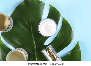 Moisturizing care skincare face cream for healing complicated troubled skin type in an open jar with visible texture. Copy space, close up, background, flat lay, top view. Monstera leaf decoration.