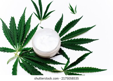 Moisturizing cream with hemp oil on a white background with hemp leaves. Natural skin care