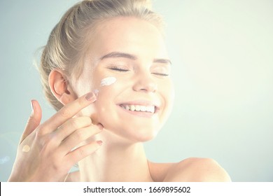 Moisturizing Summer Skin Care Sunscreen. Beautiful Model Applying Cosmetic Cream Treatment On Her Face. Rays Of The Sun Illuminate The Happy Face Of Young Women