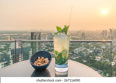 Mojito Cocktail And Cashews On Table In Rooftop Bar