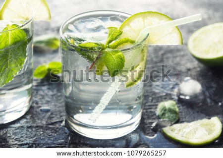 Mojito cocktail with lime and mint in glass at sunlight. Closeup photo.