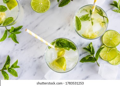 Mojito Cocktail Or Mocktail, Traditional Fresh Drink With Lime And Mint. With Paper Straws In The Drinks. Top View, From Above. On A White Marble Table.