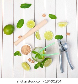 Mojito Cocktail On Wooden Table With Lime, Mint, Sugar, Muddler And Ice Crusher