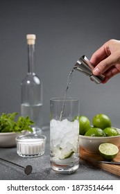 Mojito cocktail preparation. Man's hand pouring rum with a jigger into a glass