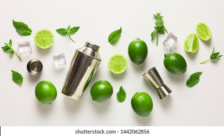 Mojito lime set, flat lay on white background. Concept: Mojito Cocktail. Whole juicy limes with ice and cocktail shaker. Concept: summer refreshing cocktail.