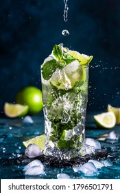 Mojito with splash and drops. Cocktail or mocktail with lime, mint, and ice in glass on blue background. Summer cold alcoholic non-alcoholic drink,  beverage and cocktail. Copy space