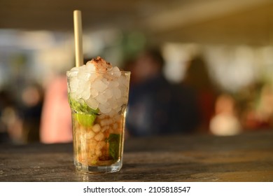 Mojito At Sunset At A Beach Bar With People In The Background Out Of Focus.