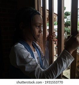 Mojokerto, Indonesia. February 23, 2021. Portrait of the girl from the wooden window smiling and happy