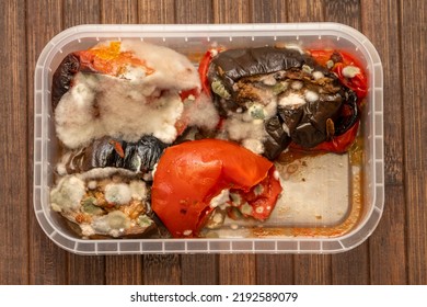 Mold Spores On Fried Vegetables In A Plastic Food Container On A Textured Wooden Background. Concept: Decomposition Products, Food Poisoning.