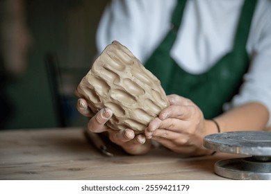 Molding handmade ceramics. Table in pottery studio with female artist shaping wet clay for potter pot or vase. Cropped image of ceramist master or craftswoman shaping kitchenware in creative workplace - Powered by Shutterstock