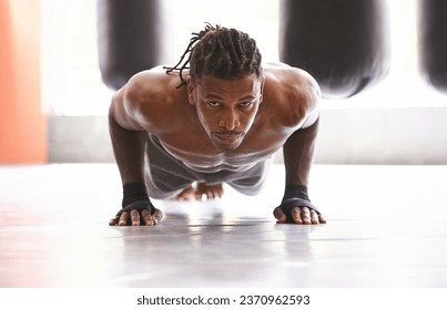 Molding his body into a fighting machine. Portrait of a young boxer doing pushups in a gym.