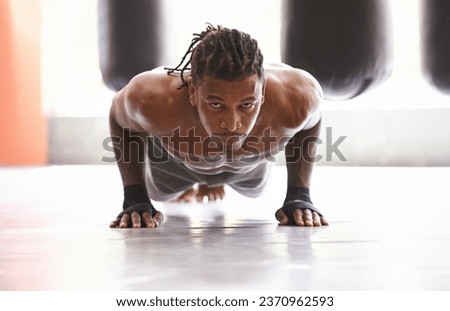 Molding his body into a fighting machine. Portrait of a young boxer doing pushups in a gym.