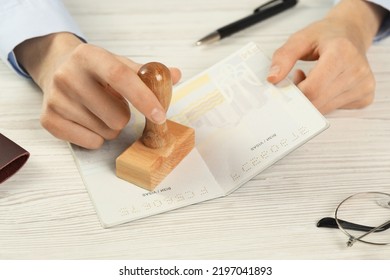 Moldova, Ceadir-Lunga - June 13, 2022: Woman Stamping Visa Page In Passport At White Wooden Table, Closeup