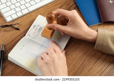 Moldova, Ceadir-Lunga - June 13, 2022: Woman Stamping Visa Page In Passport At Wooden Table, Closeup