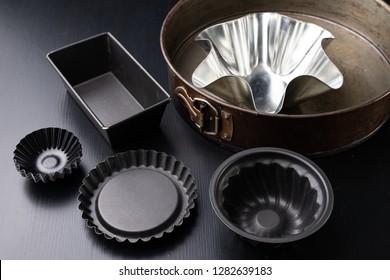 Molds for baking cakes in the home kitchen. Old dusty kitchen accessories. Dark background.