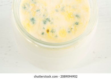 Moldy Yogurt, Top View Of Closeup Rotten Moldy Yogurt Or Yoghurt In Jar On Wooden Background. Rotten Dairy Product Or Milk