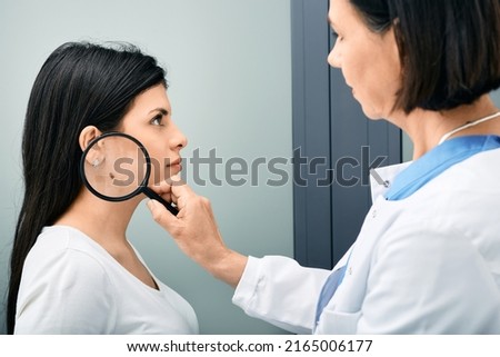 Mole dermoscopy, preventive of melanoma. Doctor examining woman's neck with mole or birthmark using magnifying glass