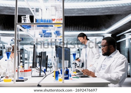Molecular biologist uses computer program displaying DNA data analysis interface in laboratory. African american man using bioinformatics genomics software on PC in sterile lab environment