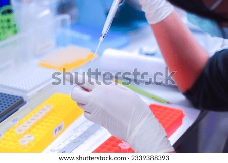 A molecular scientist is manipulating and analyzing samples to perform sequencing on that living sample on Science's Day. A technician is preparing samples with a micropipette.