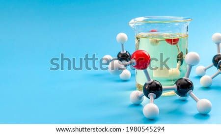 Molecular structure of chemical compounds and organic chemistry concept with educational plastic model of ethanol molecules and glass flask isolated on blue background with copy space