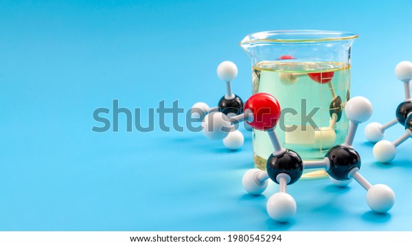 Molecular\
structure of chemical compounds and organic chemistry concept with\
educational plastic model of ethanol molecules and glass flask\
isolated on blue background with copy\
space