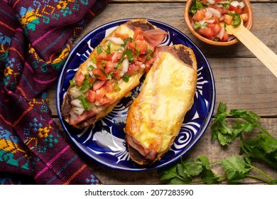 Molletas con jamón, frijoles fritos y queso fundido en un fondo gris. Gastronomía mexicana tradicional