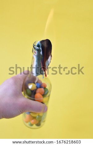 Molotov cocktail filled with colored chocolate beans as a symbol of childlike and youthful rebellion - pupillary resistance, colorful
