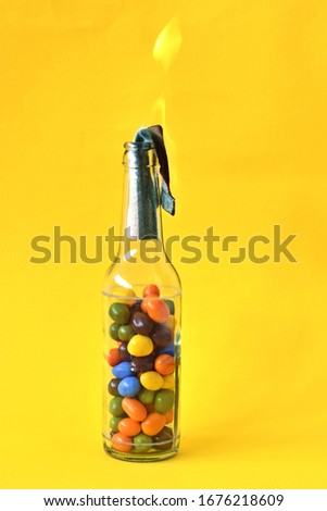 Molotov cocktail filled with colored chocolate beans as a symbol of childlike and youthful rebellion - pupillary resistance, colorful