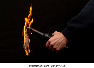 Molotov cocktail is ignited with a lighter on a dark background, close-up, selective focus. Concept: street riots, revolutionary movement, defense and defense, war in Ukraine. - Shutterstock ID 2143490155