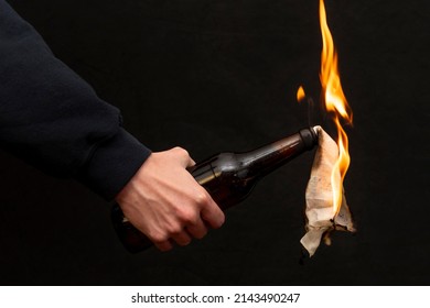 Molotov cocktail is ignited with a lighter on a dark background, close-up, selective focus. Concept: street riots, revolutionary movement, defense and defense, war in Ukraine. - Shutterstock ID 2143490247