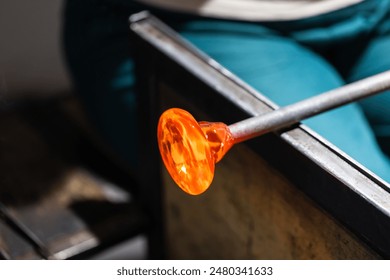 Molten glass blank rotates on blowing pipe at glass-blowing studio - Powered by Shutterstock