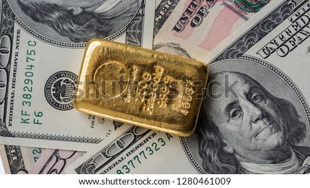 Molten gold bar weighing 250 gram against the background of dollar bills. 
