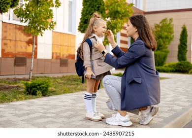 mom accompanies her first-grader daughter to school, kissing her and hugging her, back to school, the parent gives the child to the first grade. Mom meets a student from school.