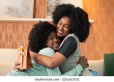 Mom appreciates the Mother's Day gift that her teenage daughter handed to her living room sofa - Powered by Shutterstock