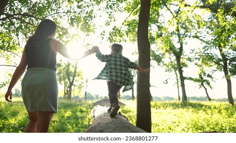 mom and baby boy play in the forest park. close-up child feet walk on fallen tree log. happy family kid dream concept. mom and child in sneakers walk on a fallen tree in park lifestyle - Powered by Shutterstock