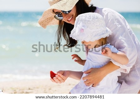 Mom and baby eat strawberry at beach