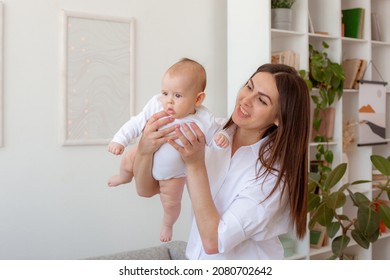 Mom And Baby Are Messing Around At Home, Baby Is Flying.Happy Maternity Leave Time. A Mother Enjoys Spending Time With Her Cute Baby, Free Space