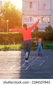 Mom And Baby Play Hopscotch On The Playground During Sunset