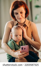 Mom With Baby Watching To Smart Mobile Phone Videos Or Work Text