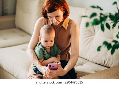 Mom With Baby Watching To Smart Mobile Phone Videos Or Work Text