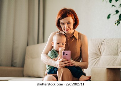 Mom With Baby Watching To Smart Mobile Phone Videos Or Work Text