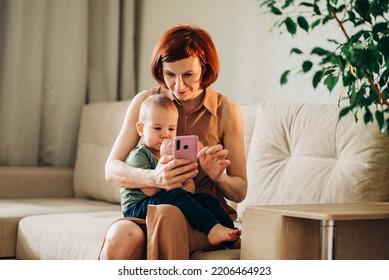 Mom With Baby Watching To Smart Mobile Phone Videos Or Work Text