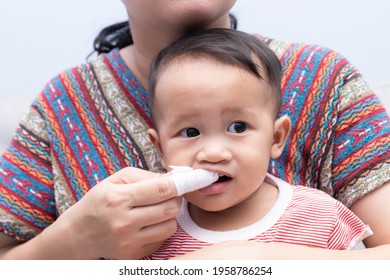 Mom Brushes Baby's Teeth With Gauze That Fits On Her Finger. Kids Hygiene Concept