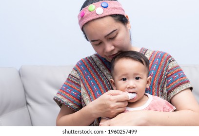 Mom Brushes Baby's Teeth With Gauze That Fits On Her Finger. Kids Hygiene Concept