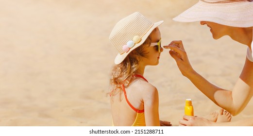 Mom carefully smears her child's face with protective cream on the beach. Skin care. Protection from the sun. Sunscreen for children.