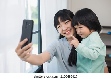 Mom Carry Son Using Smartphone Video Call To Say Hi With Family Stay At Home. Mother Holding Little Boy Hugging Shared Happy Moment On Social Media Walking In Living Room.