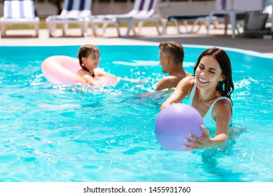 Mom catching ball. Happy mom catching the ball in swimming pool while having fun together - Shutterstock ID 1455931760