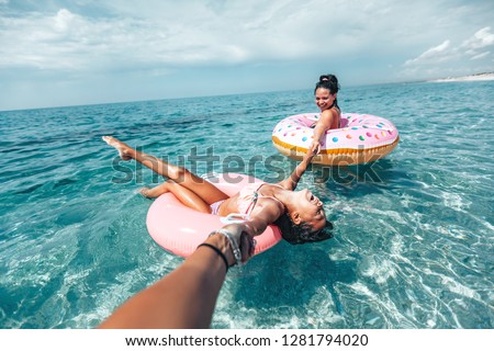 Mom with child chilling on lilo in the sea water. Family relaxing on inflatable rings on the beach. Summer vacations, idyllic scene.