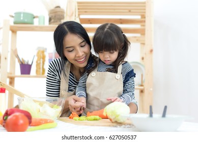 Mom And Child Cooking And Cutting Vegetables On Kitchen