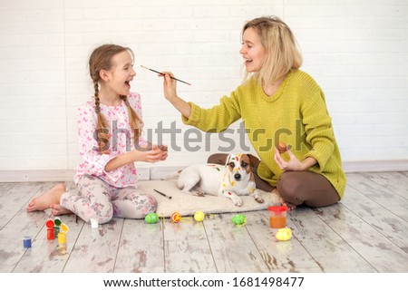 Mom and child decorate Easter eggs. Family at home. Woman with girl painting
